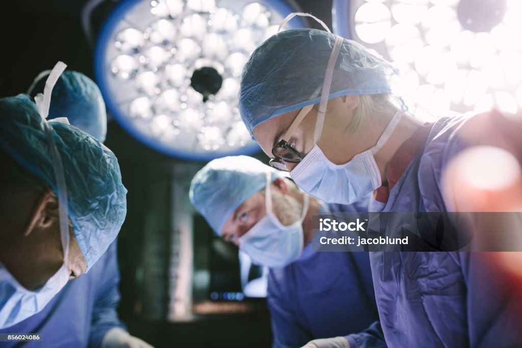 Concentrated surgeon performing surgery with her team Concentrated female surgeon performing surgery with her team in hospital operating room. Medics during surgery in operation theater. Surgery Stock Photo