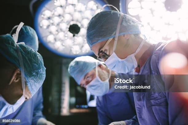 Concentrated Surgeon Performing Surgery With Her Team Stock Photo - Download Image Now