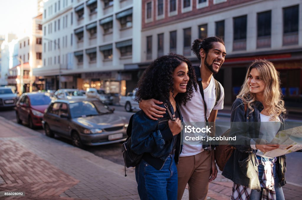 Group of friends exploring the city Woman tourist using navigation map to explore the city. Man with two women friends moving around the city. City Stock Photo