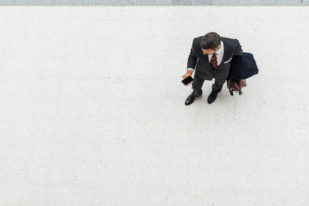 Young businessman carrying luggage while running on the street and checking time on his wristwatch.