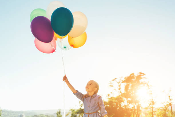 Happiness teen girl with colorful balloons enjoy in the morning time at grassland. Happy birthday party. vintage color tone effect