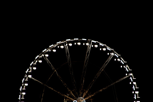 A ferris wheel cropped in half at night time