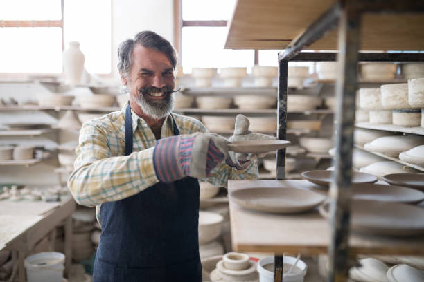 istock Happy male potter placing plate ob shelf 856059744