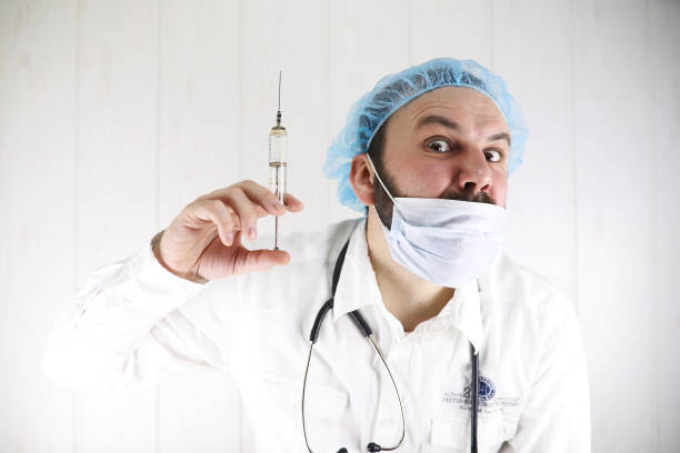 istock Crazy bearded doctor in a white coat and old syringe 856080188