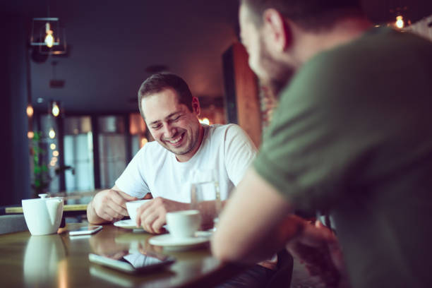 istock Two Smiling Friends Drinking Coffee and Socialising in a Cafe 856080706