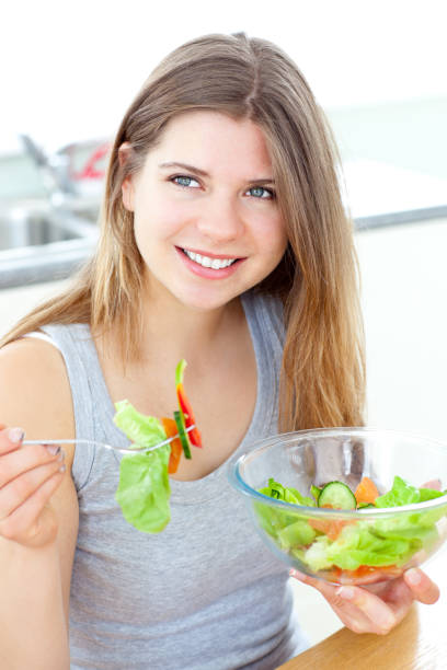 istock Smilling woman eating salad in the kitchen 856094736