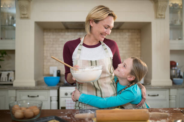 istock Daughter hugging mother while preparing cookies in kitchen 856098308
