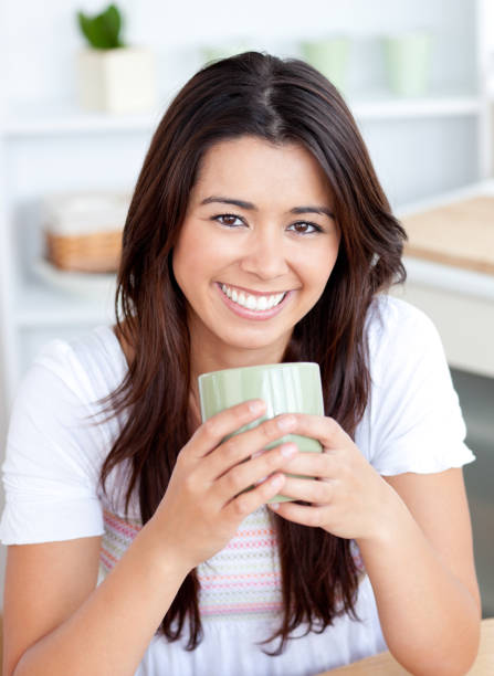 istock Handsome woman drinking coffee in the kitchen smiling at the camera 856104702