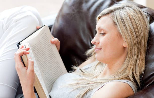 istock Charming woman reading a book sitting on a sofa 856105490