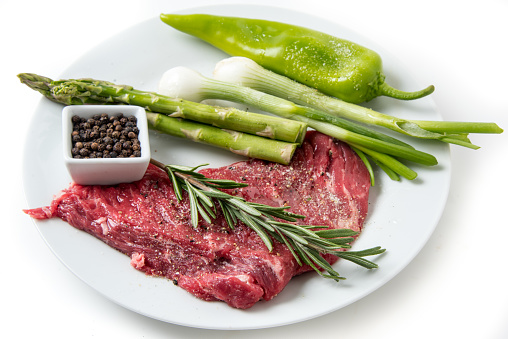 Raw Beef Steak with its cooking ingredients: pepper, asparagus,Rosemary and sweet onions