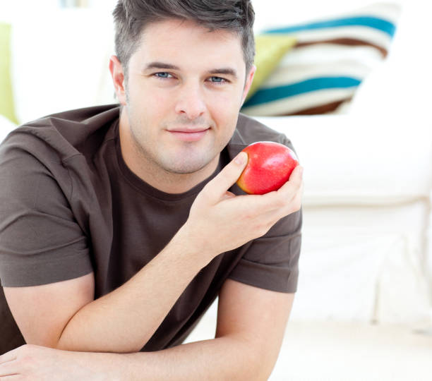istock Jolly man holding a red apple lying on the floor 856120082