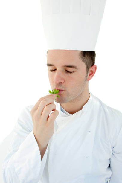 istock Young cook with closed eyes tasting a herb against white background 856122326