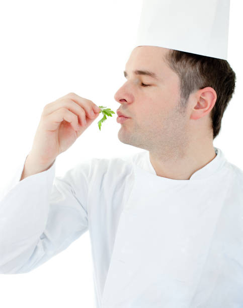 istock Charming young cook with closed eyes holding a herb against white background 856122356