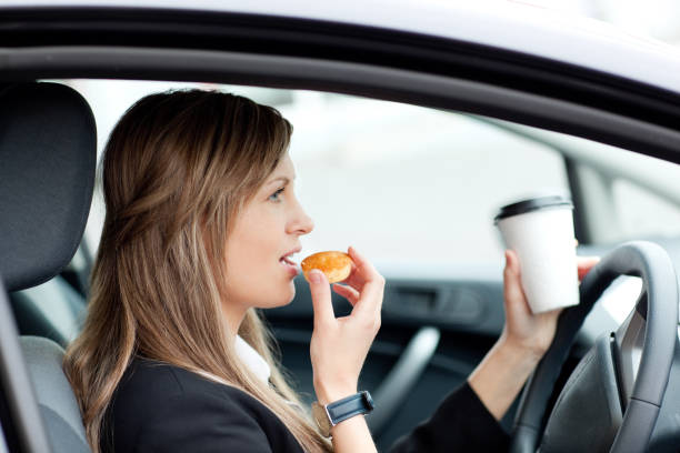 istock Charming businesswoman eating and holding a drinking cup while driving 856122868