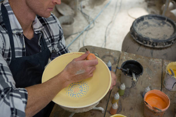 istock Male potters painting a bowl in pottery workshop 856126456