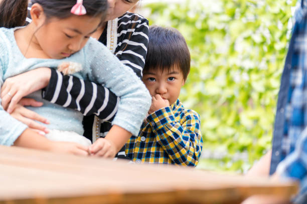 Young boy hiding behind his mother looking worried. Osaka, Japan. September 2017