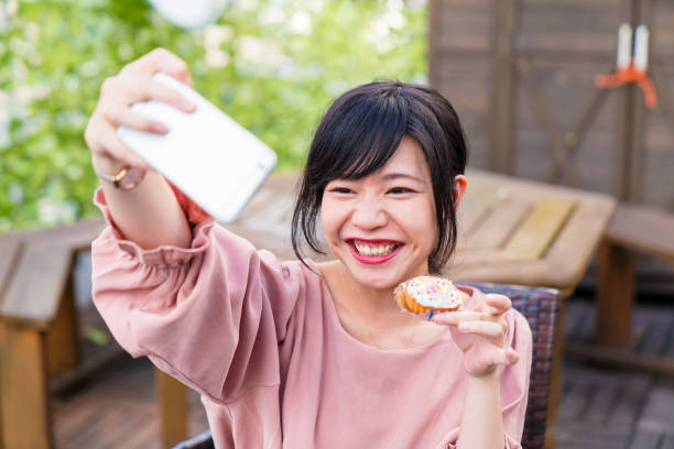 istock Young woman taking a selfie whilst holding a cupcake 856126664