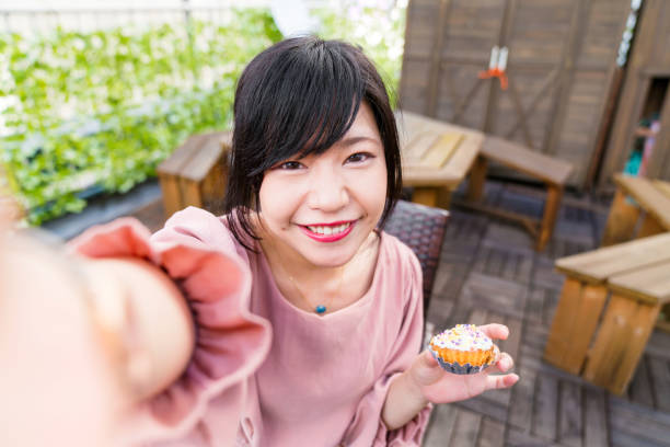 Young woman taking a selfie whilst holding a cupcake