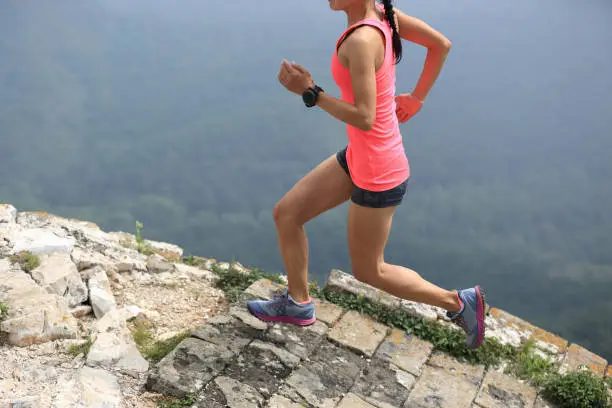 Photo of young woman trail runner running on great wall on the top of mountain