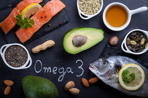 Black slate table with product rich in omega 3 and vitamin D. Written word omega 3 by white chalk.