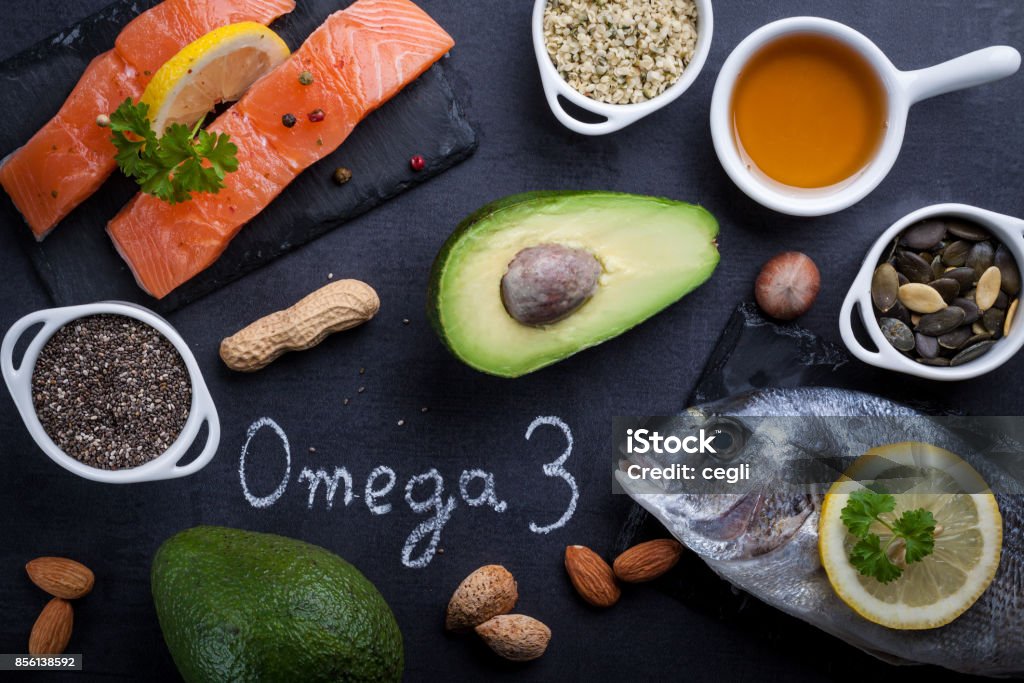 Black slate table with product rich in omega 3 and vitamin D. Written word omega 3 by white chalk. Omega-3 Stock Photo