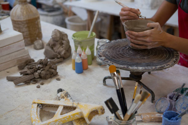 istock Female potter molding a mug with hand tool 856145242