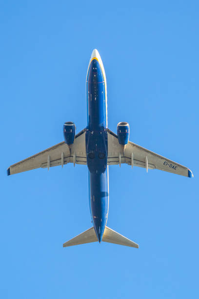 ryanair plane in the sky Bologna, Italy - December 20, 2016: low angle view of a Ryanair plane against sky, close up fling. blue Ryanair, low cost flights company, passenger airplane flight against blue background below view. landing craft stock pictures, royalty-free photos & images