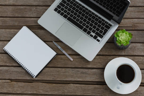 istock Laptop, notepad, pen, pot plant, and coffee on wooden plank 856153024