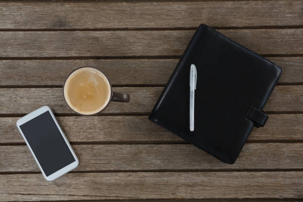 istock Mobile phone, coffee, pen and organizer on wooden plank 856153236