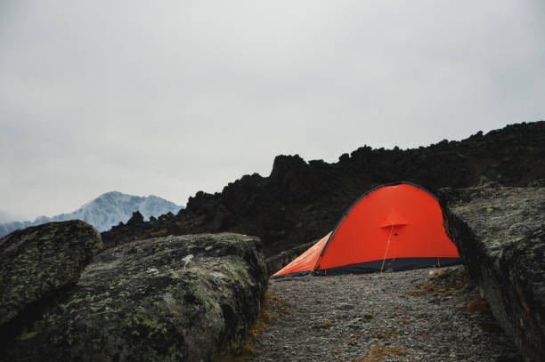istock An orange tent stands high in the mountains between two high rocks 856156040