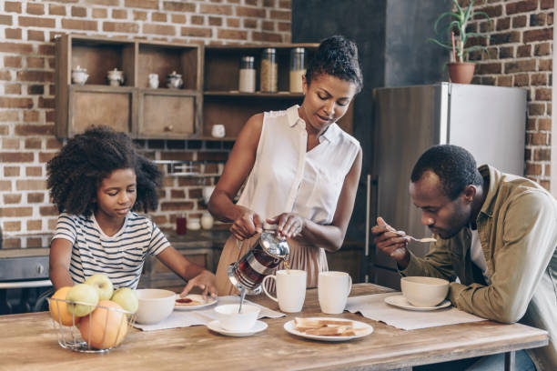 Family having breakfast Woman pouring coffee into cups while her family is having breakfast the black womens expo stock pictures, royalty-free photos & images