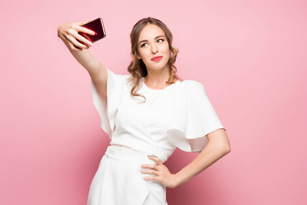 retrato de una joven atractivo que selfie foto con el smartphone en un fondo rosa - made man object fotografías e imágenes de stock