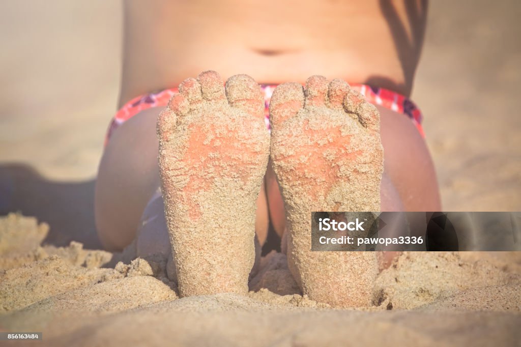 Little girls feet in the beach sand Close up of a feet of a little girl sitting on the beach in summer Barefoot Stock Photo