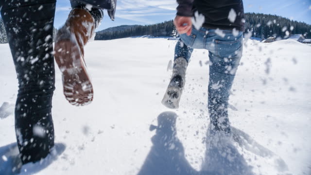 Two young women running in fresh snow, enjoying their winter break, shot from the waist down