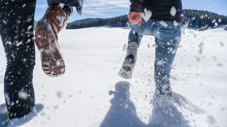 Two young women running in fresh snow, enjoying their winter break, shot from the waist down
