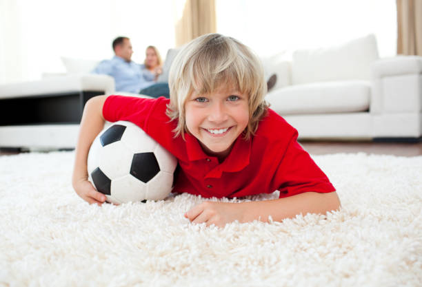 istock Smiling boy watching football match lying on the floor 856173980