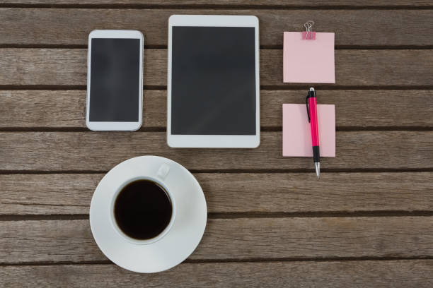 istock Black coffee, mobile phone, digital tablet, pen and sticky note on wooden plank 856177094