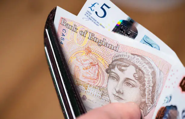 A British wallet held open to show newly issued polymer banknotes, with the £10 note featuring the 19th Century author, Jane Austen.