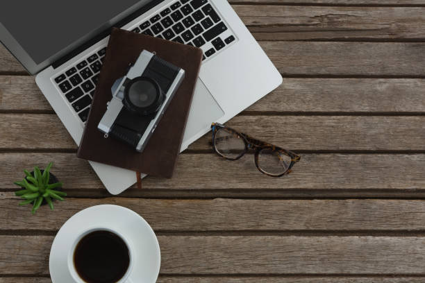 istock Black coffee, camera, pot plant, spectacles, organizer and laptop on wooden plank 856178570