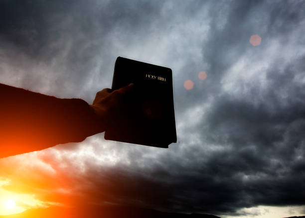 istock Hand holds bible up towards grey clounds 856184940