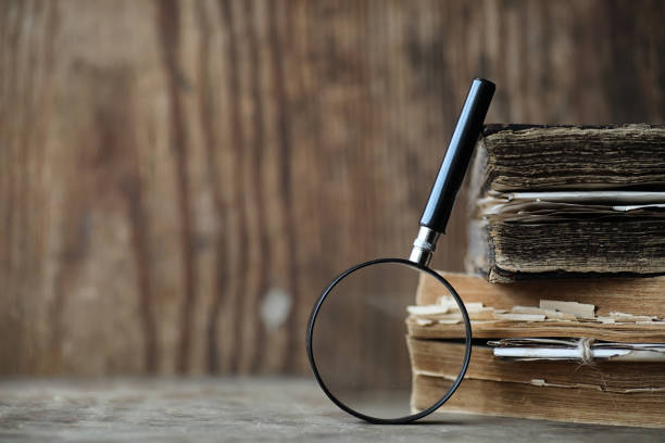 Old books on a wooden table and glass magnifier