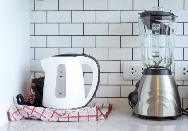 chaleira elétrica de aço inoxidável e liquidificador em cerâmica com plugue no quarto de cozinha no fundo branco moderno em casa - electric juicer - fotografias e filmes do acervo