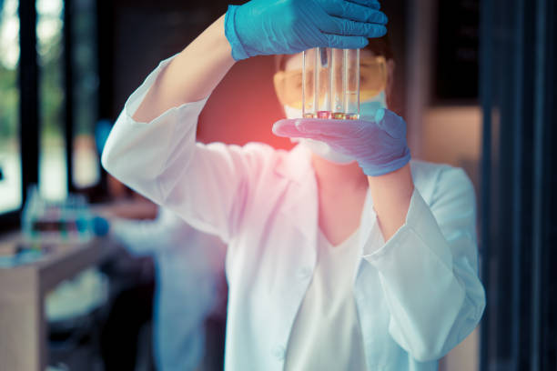 mulher cientista com óculos reserch e realiza experiências a trabalhar por compostos de síntese em laboratório e o tubo de ensaio - genetic research men chemical protective glove - fotografias e filmes do acervo