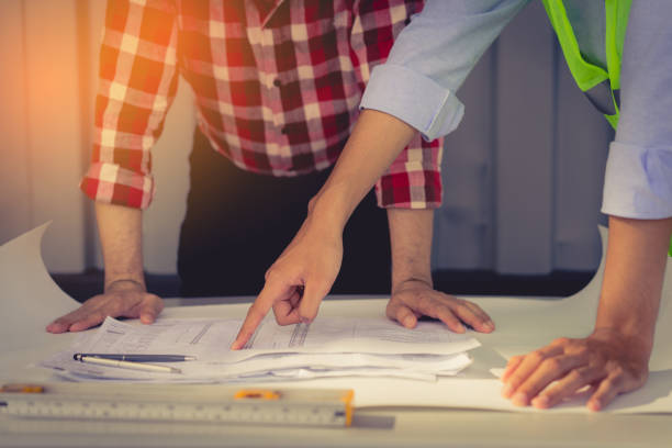 istock Engineer men with safety helmet consult teamwork partner and join group successful project building construction with level finger pointing plan. 856200836