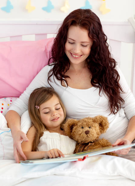istock Happy mother and daughter reading in bed 856211840