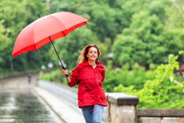 istock Happy young woman walking with umbrella under the rain 856211888
