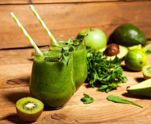 istock Freshly blended green smoothie in glasses with straws. Wooden background. 856255992
