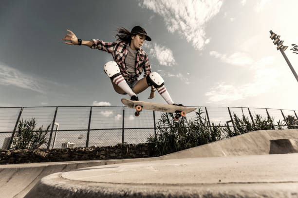 Giovane donna che salta con lo skateboard - foto stock