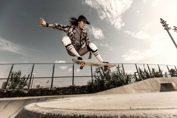 Young woman jumping with skateboard Young woman jumping in skateboard park skateboarding stock pictures, royalty-free photos & images