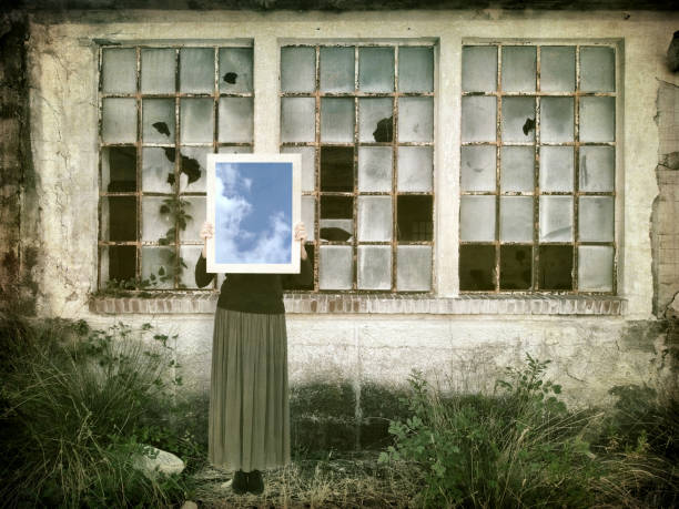 istock Hope in desolation. Woman with mirror reflecting blue sky in derelict environment. 856288990